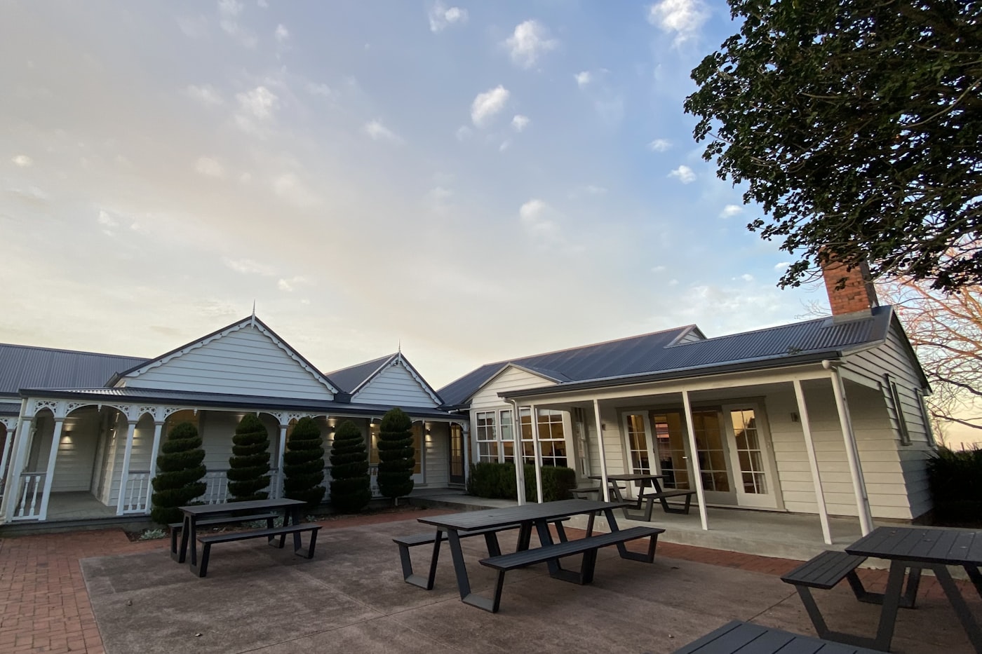 A cream weatherboard villa with a bullnose veranda, turned posts and fretwork gables under a corrugate roof, Auckland